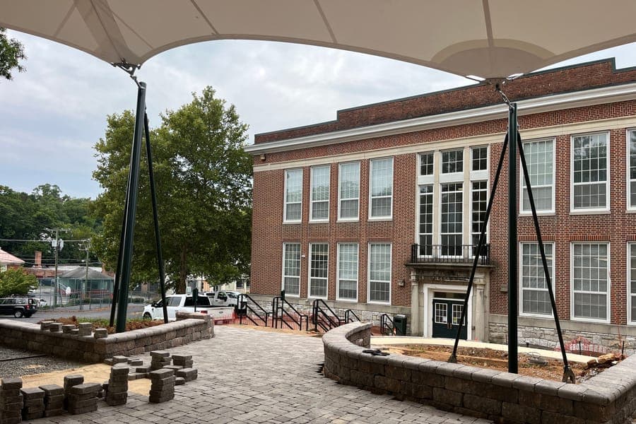 The new terrace beside the Staunton Public Library, with a white shade sail on green posts and curved stone seating walls